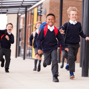 Four primary school children smiling and running into school