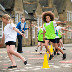 Group of children running in the playground around a cone