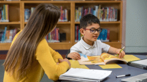 Woman observing a young person as he reads a book in a library